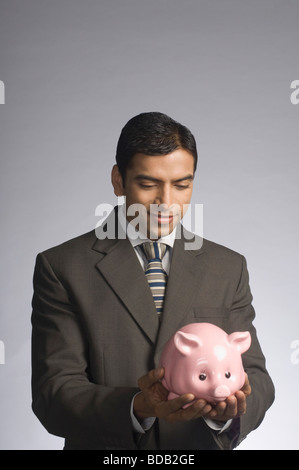 Geschäftsmann hält ein Sparschwein Stockfoto