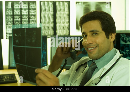 Männlichen Arzt Untersuchung eine Röntgenaufnahme und am Telefon sprechen Stockfoto