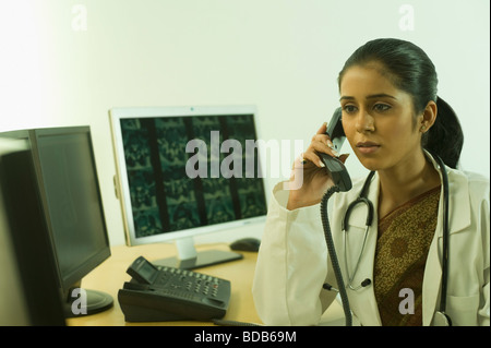 Ärztin untersucht eine Röntgenaufnahme und am Telefon sprechen Stockfoto