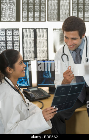 Ärztin mit einem männlichen Arzt untersucht einen Röntgen-Bericht Stockfoto