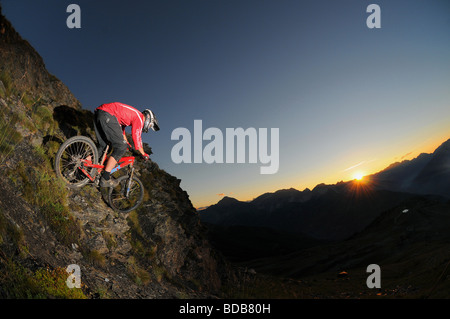 Ein Mountainbiker fährt entlang einer felsigen Grat bei Sonnenuntergang hoch über dem Skigebiet von Sauze D'oulx in den italienischen Alpen Stockfoto