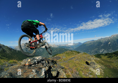 Ein Mountainbiker fährt mit einem Felsgrat hoch in den Bergen oberhalb von Sauze D'oulx in den italienischen Alpen. Stockfoto