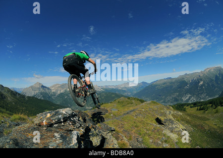 Ein Mountainbiker fährt mit einem Felsgrat hoch in den Bergen oberhalb von Sauze D'oulx in den italienischen Alpen. Stockfoto