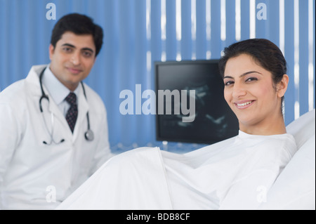 Porträt einer schwangeren Frau mit einem männlichen Arzt im Hintergrund Stockfoto