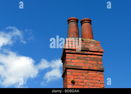 Ziegel-Schornstein gegen ein strahlend blauer Himmel mit Wolken flauschige weiße whispy Stockfoto