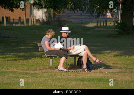 Paar Sat auf einer Bank-Lesung In der Abendsonne Stockfoto