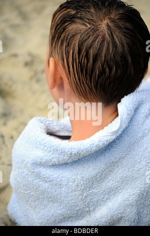 Royalty free Foto eines jungen am Strand im Sommer mit Handtuch umwickelt ihn nach dem Schwimmen an der britischen Küste UK Stockfoto