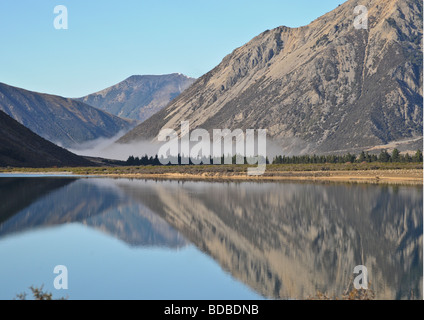 Panoramasicht auf Berge mit Wolken im Tal und seine atemberaubende Spiegelungen im Wasser in Arthurs Pass Region von NZ. Stockfoto