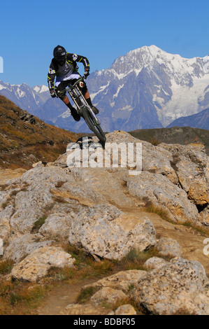 Ein Mountainbiker fährt mit einem Felsgrat mit dem Mont Blanc im Hintergrund hoch über Pila in den italienischen Alpen. Stockfoto