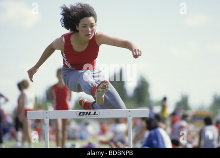 Junge Hispanic Frau erwärmt sich für Damen Low Hurdle Race High School Senior, New Mexico State AA Track & Feld Stockfoto