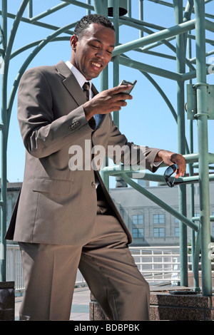 Geschäftsmann, Prüfung seines Mobiltelefons lächelnd im freien Stockfoto