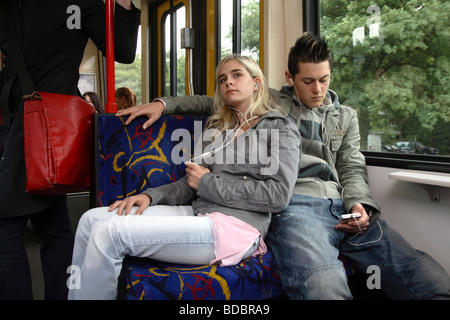 Junges Paar in einer Straßenbahn, Musik hören, Essen, Deutschland Stockfoto