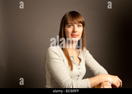 Oberkörper Porträt einer Frau mit langen braunen Haaren und blauen Augen, die im Studio sitzen. Stockfoto