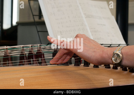 Detail von einem chinesischen Zheng aka Guzheng zeigt die Biegung der Zeichenfolge mit den Fingern um unterschiedliche Effekte zu erzielen Stockfoto