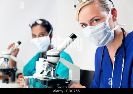 Eine blonde medizinische oder wissenschaftliche Forscherin oder Arzt mit ihrem Mikroskop im Labor Stockfoto