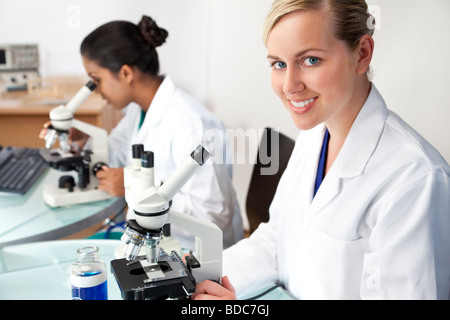 Eine blonde medizinische oder wissenschaftliche Forscherin oder Arzt mit ihrem Mikroskop im Labor Stockfoto