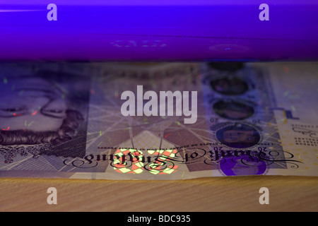 mit Hilfe eines UV schwarz-Lichts eine zwanzig Pfund Anmerkung Bank von England Banknoten zu überprüfen, ob es echt ist Stockfoto