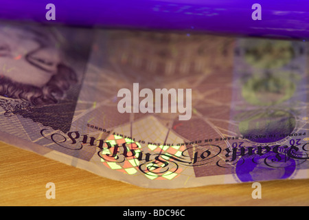 mit Hilfe eines UV schwarz-Lichts eine zwanzig Pfund Anmerkung Bank von England Banknoten zu überprüfen, ob es echt ist Stockfoto