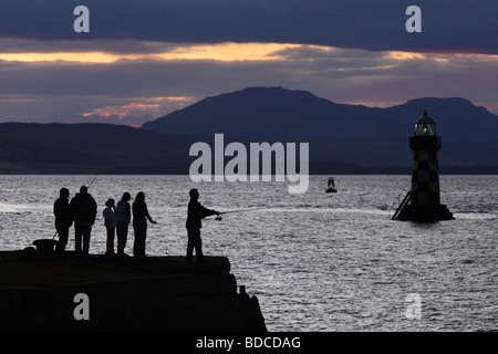 Gruppe von Menschen, die bei Sonnenuntergang auf dem Firth of Clyde, Port Glasgow, Schottland, Großbritannien fischen Stockfoto