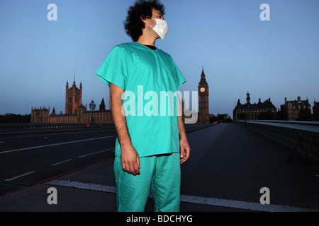 Junger Mann mit chirurgischer Mundschutz und jade einheitlich aussehen verloren in der Nähe der Big Ben, auf Parlament Brücke, London. Stockfoto