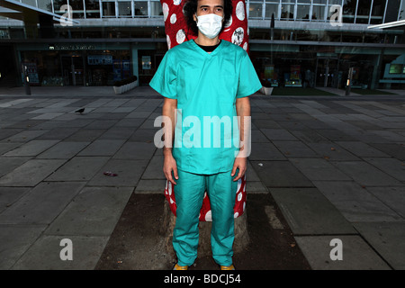 Junger Mann Stand Bausteinennicht auf der South Bank, London. Er trägt eine chirurgische Uniform und eine Gesichtsmaske. Stockfoto