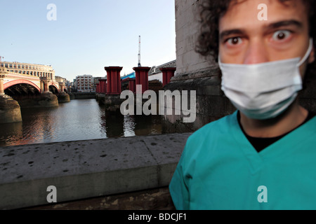 Ein junger Mann mit einem chirurgischen Gesichtsmaske und medizinische Uniform sieht erschrocken und ziemlich schockiert. Stockfoto