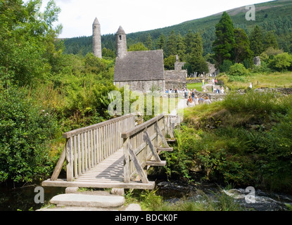 Eine hölzerne Brücke über den Fluss führt zu die Klostersiedlung in Glendalough, County Wicklow Irland 2009 Stockfoto