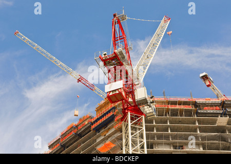 Krane auf einer Hochhaus-Baustelle rote Kräne vor blauem Himmel aufzublicken Stockfoto