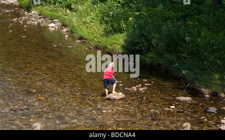 Ein kleiner Junge an einem heißen Sommertag in einem Bach in Vermont USA waten. Stockfoto