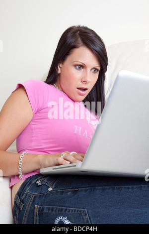 Schockiert junge Frau auf der Suche im Internet auf laptop Stockfoto