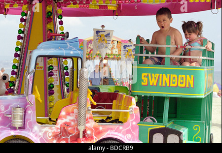 Zwei Kinder haben Spaß an einem Kreisverkehr am Meer, Weymouth Stockfoto