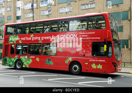 London Bus powered by Elektro-Hybrid-Technologie mit einem anderen roten Bus in Richtung Grün für London gedruckt auf der Seite England UK Stockfoto