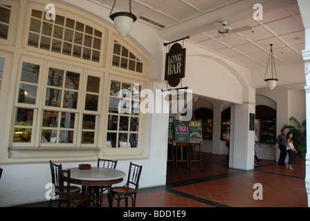 Tabelle außerhalb des Reiches Cafe und Zeichen in der Long Bar im Raffles Hotel Arcade, Raffles Hotel Arcade, Singapur Stockfoto