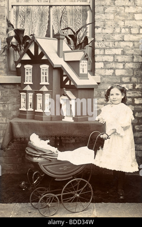 Kleines Mädchen mit Puppe Wagen & Puppenhaus Stockfoto