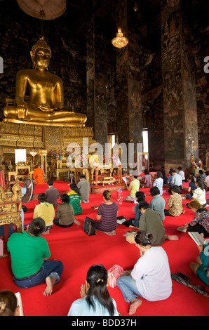 Touristen und einheimische Thais knieten im Gebet vor einer großen Buddha-Statue in einem Tempel in Thailand Stockfoto