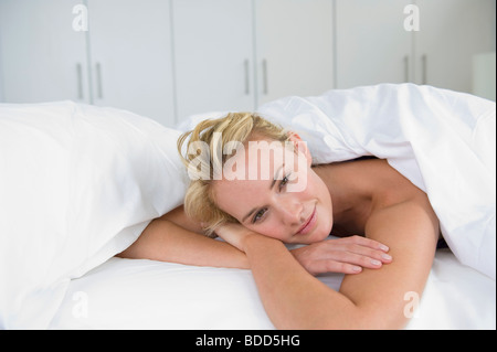 Nahaufnahme einer Frau auf dem Bett liegend und lächelnd Stockfoto