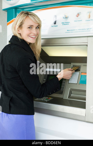 Frau ATM eine Kreditkarte einschieben Stockfoto