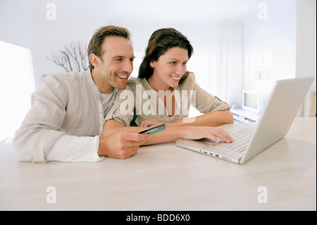 Ehepaar hielt eine Kredit Karte und arbeiten auf einem laptop Stockfoto