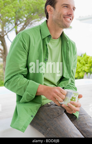 Mann hält eine Kaffeetasse und lächelt Stockfoto