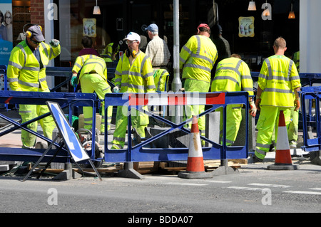 Menschenmenge oder Gruppe von Arbeitern in der Einkaufsstraße Modernisierung Straßen- und Straßenbelag tragen eine gut sichtbare Jacke, die hinter der Sicherheit arbeitet Barrieren England Großbritannien Stockfoto