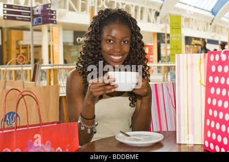 Eine schlanke attraktive trendige junge afrikanische Frau eine Kaffee-Pause in einem Shopping Center sehr glücklich auf shopping-Tour. Stockfoto