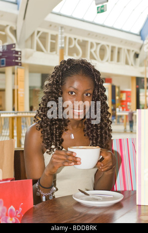 Eine schlanke attraktive trendige junge afrikanische Frau eine Kaffee-Pause in einem Shopping Center sehr glücklich auf shopping-Tour. Stockfoto