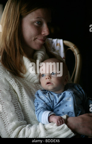 Ein vier Monate altes Baby entspannend mit seiner Mutter in den frühen Morgenstunden setzte sich in einen Schlaf-Anzug. Modell veröffentlicht Stockfoto
