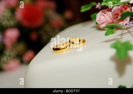 Gold Trauringe oben auf einer Hochzeitstorte Stockfoto