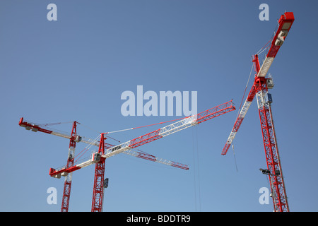 Drei rote und weiße Gebäude Krane vor blauem Himmel. Stockfoto