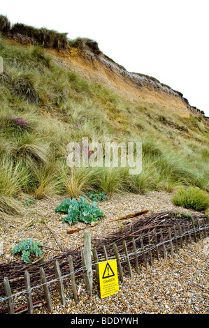 Die Klippen von Dunwich Heath, Suffolk, England - die Erosion durch das Meer - damit die gelben Warnschild Warnung unterliegen. Stockfoto