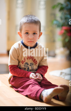 Porträt eines kleinen Jungen auf dem Boden sitzend Stockfoto