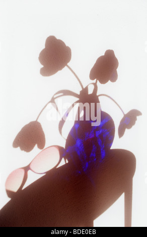 Schatten auf der weißen Wand der Rundtisch mit rosarote Sonnenbrille und Runde blaue Glasvase mit vier Tulpen Stockfoto