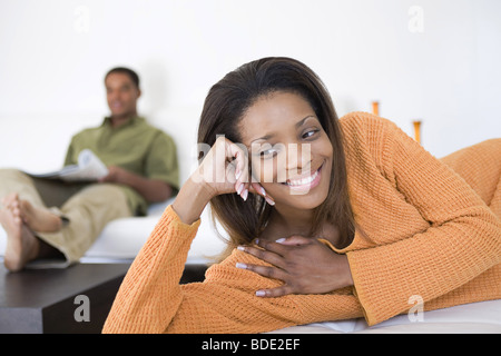 Frau auf Sofa Mann im Hintergrund Stockfoto
