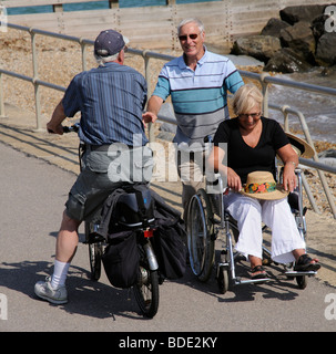 Mann, die Frau im Rollstuhl schieben, am Strand von Bognor Regis West Sussex England Südengland Stockfoto